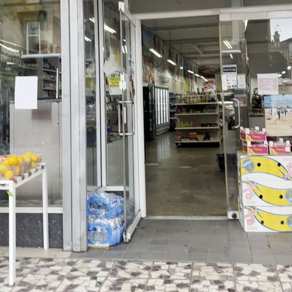 The open front door of Madina Store on Kilmarnock Road, with shelves of groceries inside